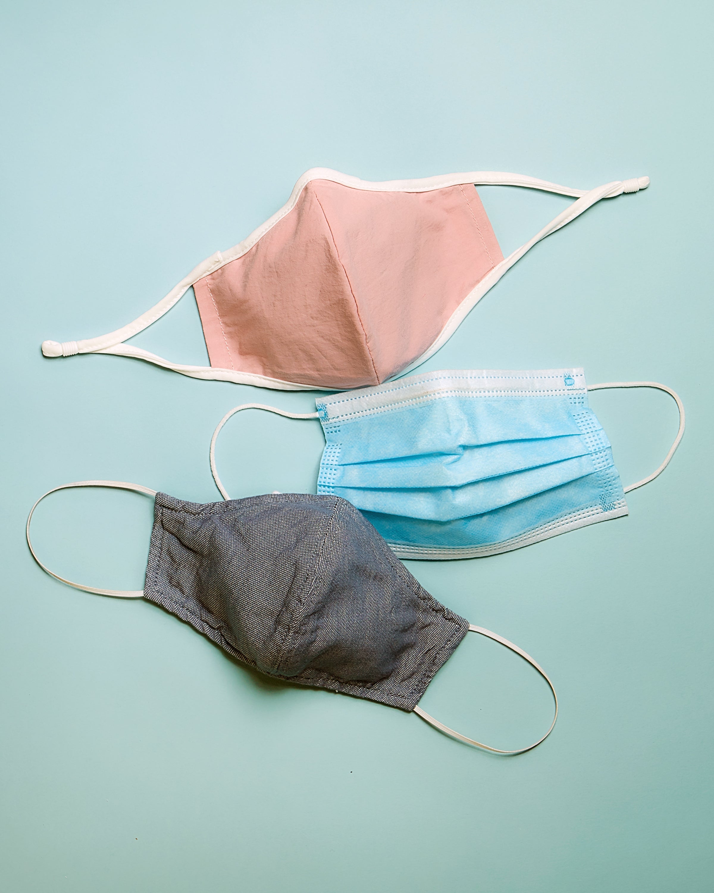 picture of a group of three different masks or face coverings. One is pink, one is a blue disposable mask and one is a denim mask made by Hedley & Bennett.