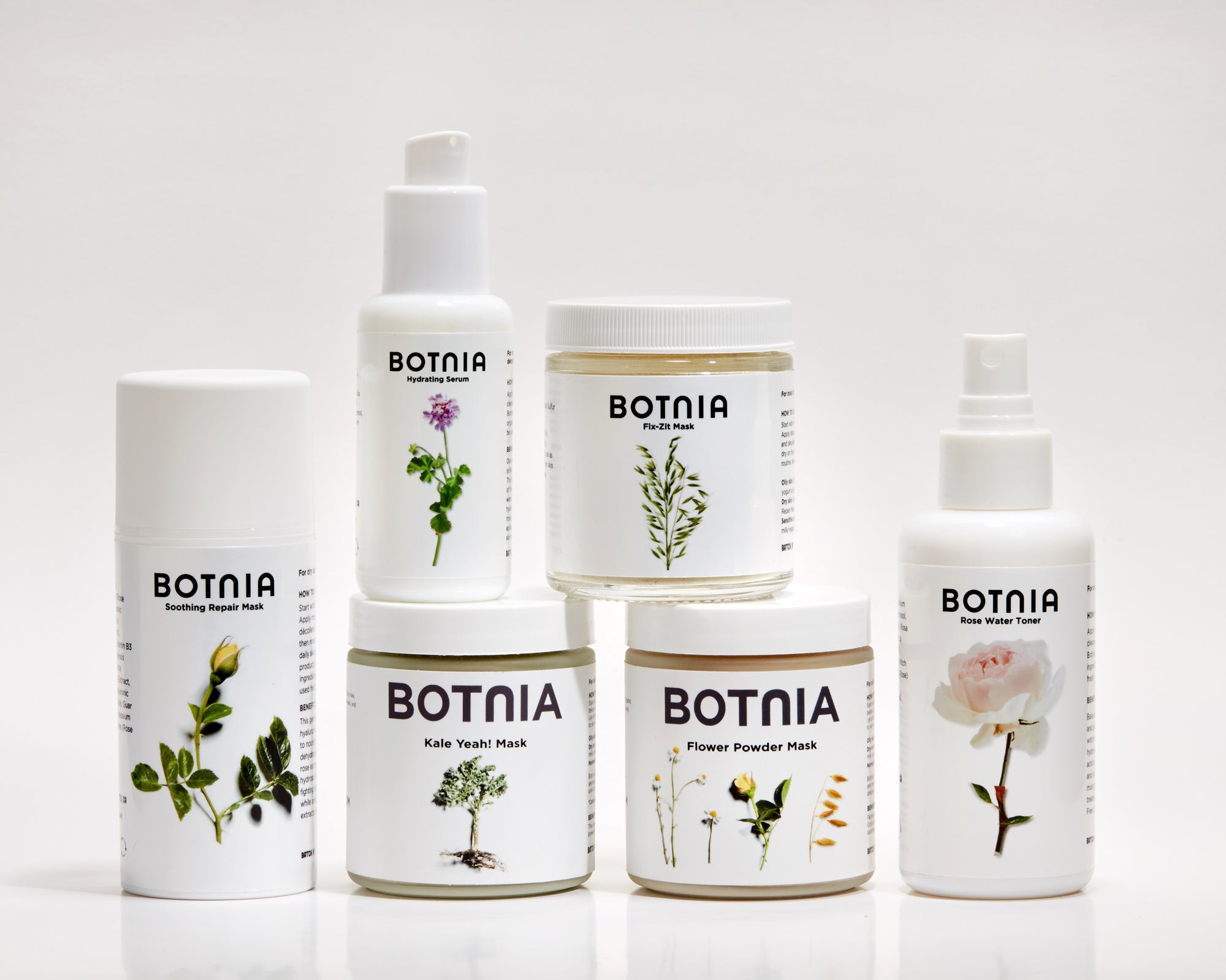 photo of six botnia skincare products, the hydrating serum, gentle cleanser, three masks and the rose water toner, with a white/grey background and light shadows.