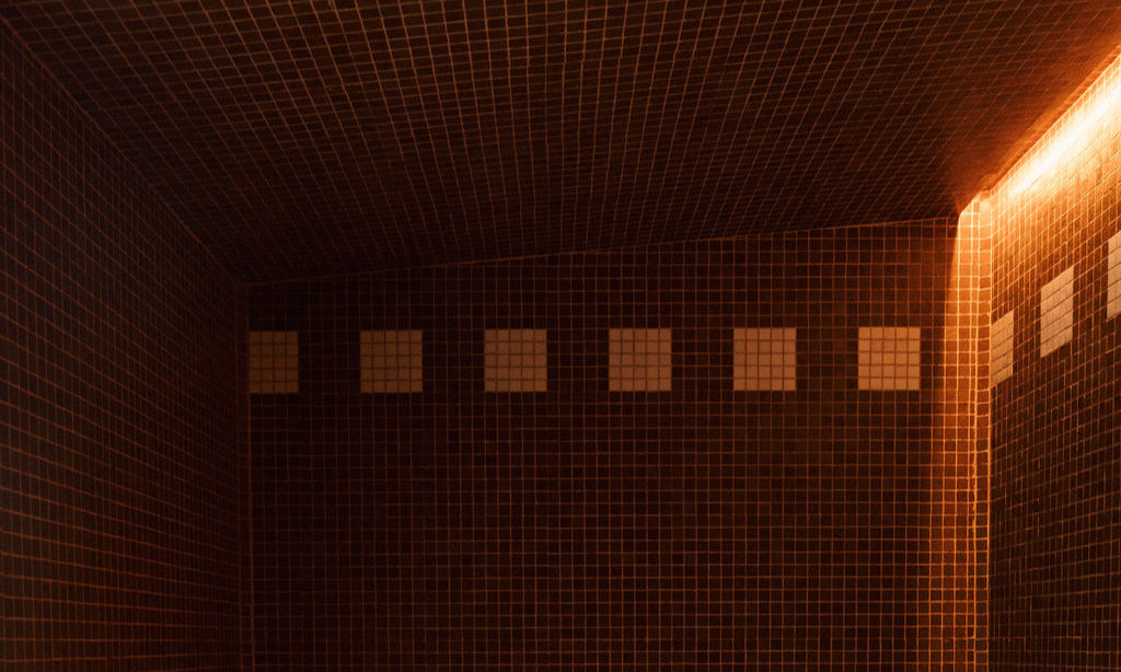 Steaming room with tiled walls and floor, illuminated by warm light.